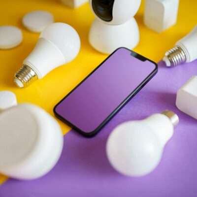 Nutitelefon ümbritsetuna nutipirnidest ja tarkadest seadmetest kollase ja lilla taustaga