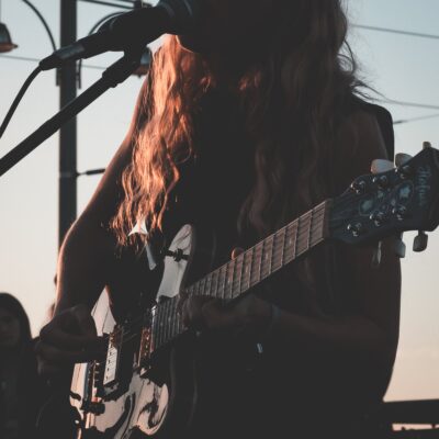 Naisartist esitab kitarril muusikapala vabas õhus.